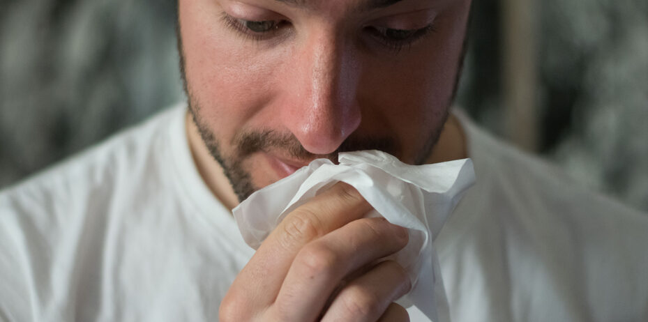 Man with Allergies wiping his Nose